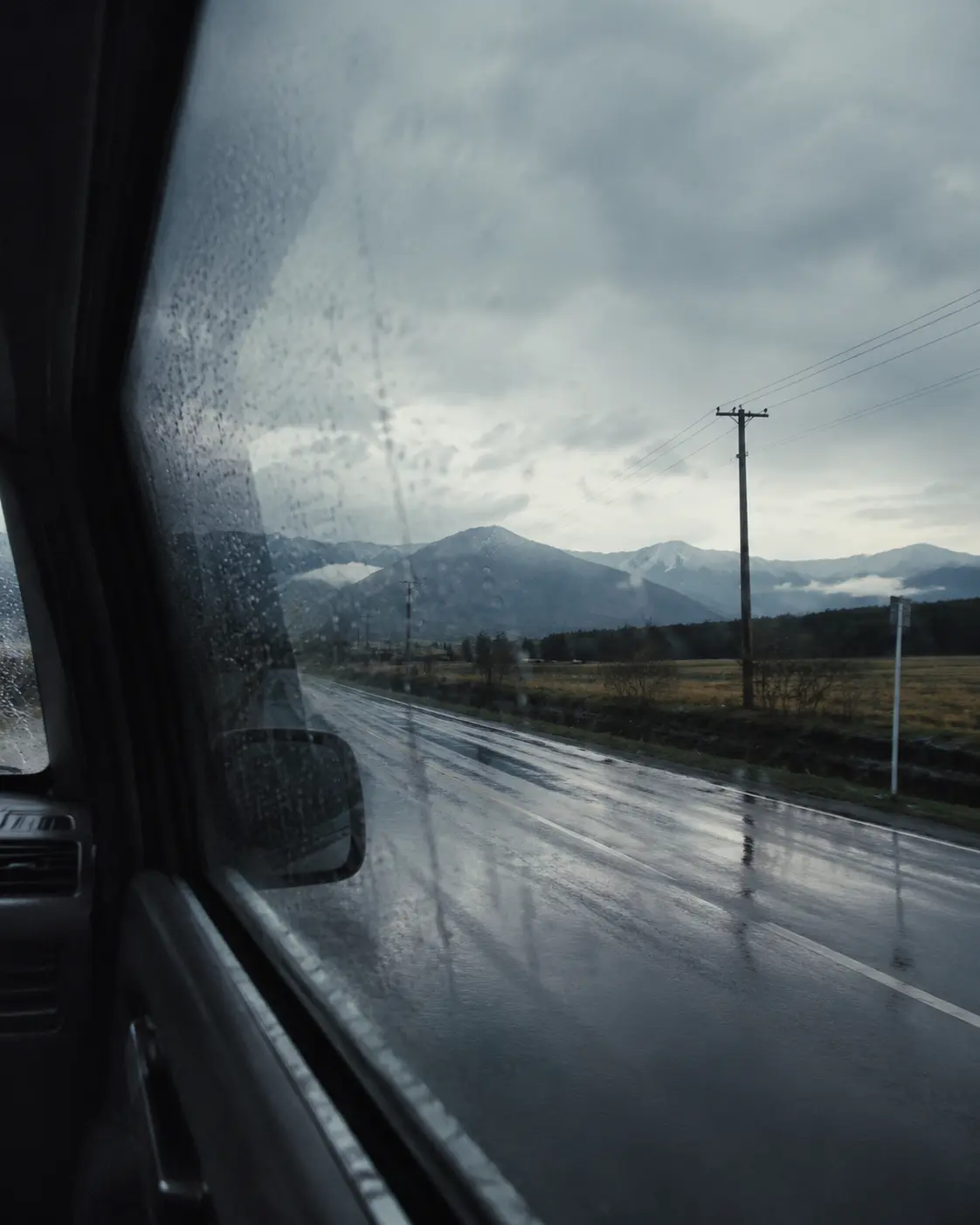 Rain on a road seen through a car window